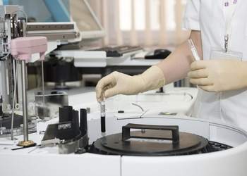 A woman is operating a Nexyta machine in a lab.