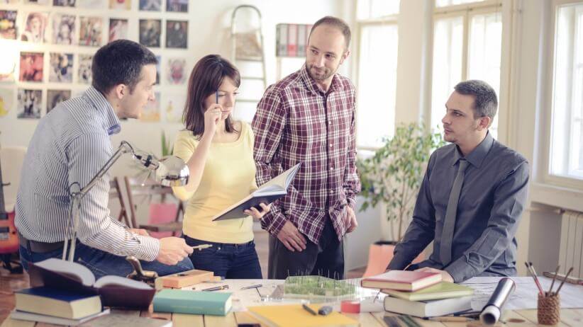 A group of people sitting around a table in an office.