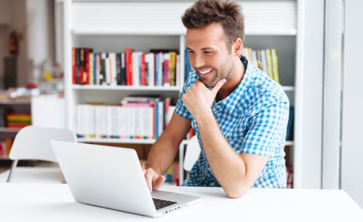 A man sitting at a desk using a laptop.